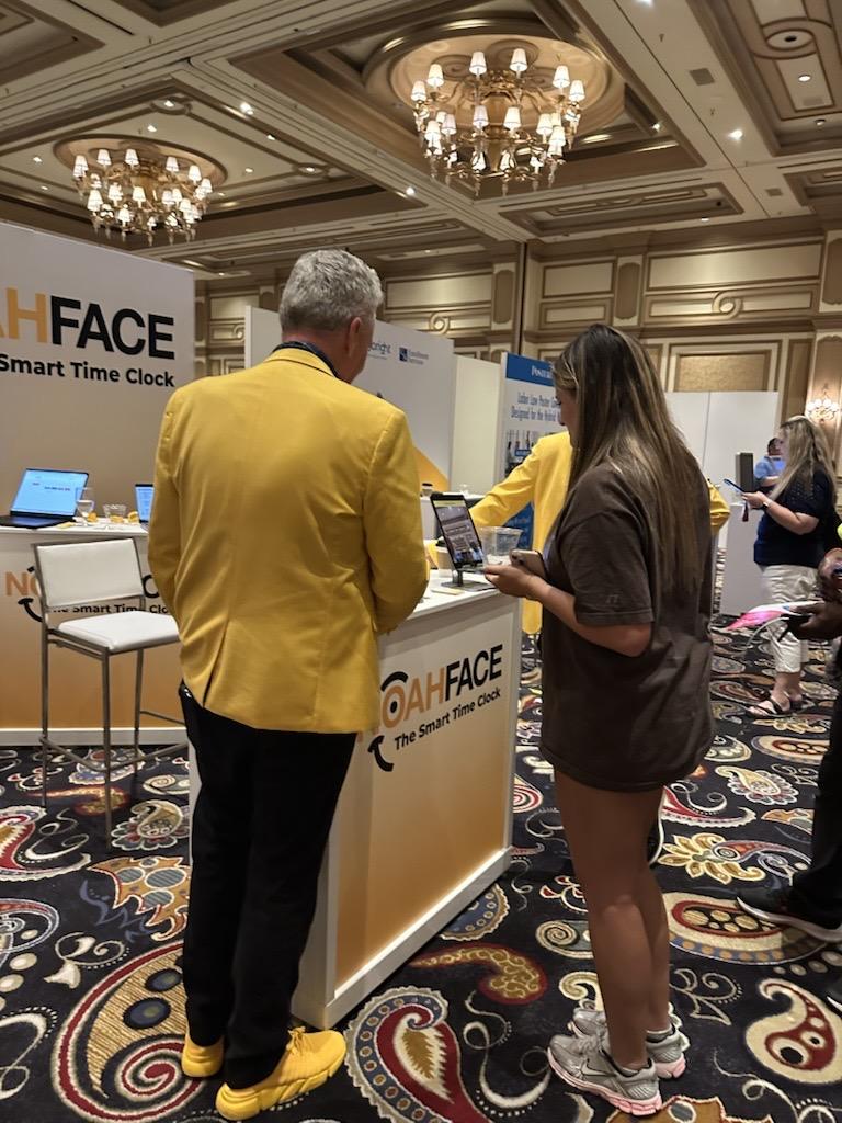 Bene-Care employee learning about NoahFace smart time clock solutions at the iSolved Connect conference booth.