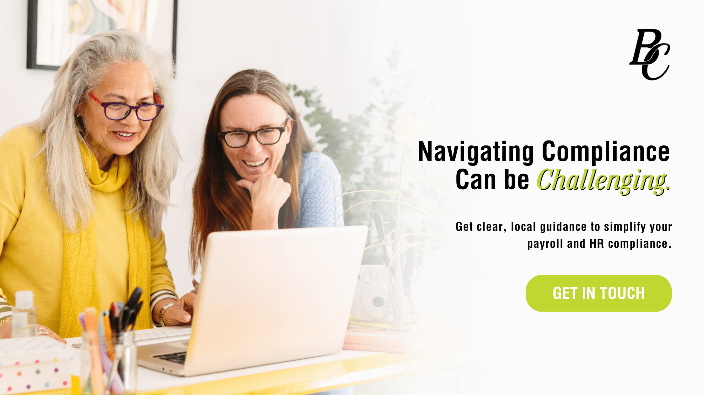 Two professionals reviewing compliance information together on a laptop, representing Bene-Care’s supportive HR and payroll guidance.